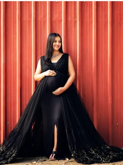 An outdoor shot with an industrial feel. The contrast between the elegant black gown and the red container wall is striking and modern.