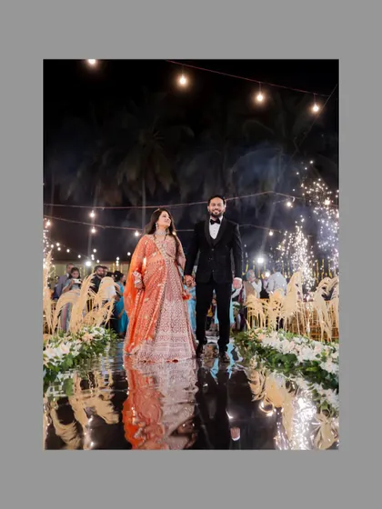 The couple makes a grand entrance at their outdoor reception, walking on a reflective aisle flanked by sparklers.