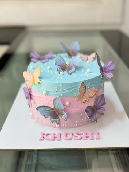 A whimsical butterfly cake with a pink and blue watercolor effect. The edible butterflies seem to flutter around the cake.