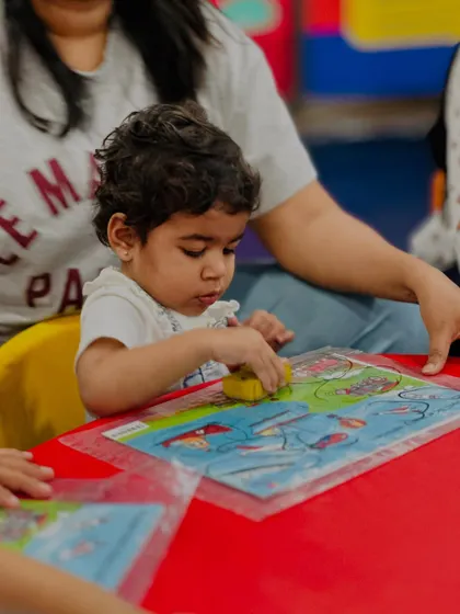 A young boy concentrates on a puzzle, his focus demonstrating the development of problem-solving skills. Our activities are designed to be challenging yet achievable, building confidence with every success.