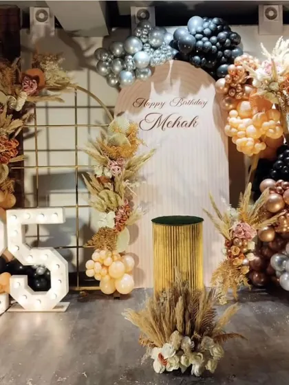 The full, breathtaking setup for a boho-glam 25th birthday, featuring multiple backdrops, pampas grass arrangements, and marquee numbers.