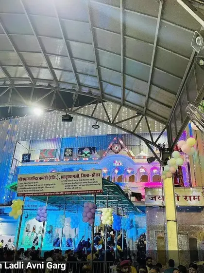 The exterior view of the temple decorated for a Khatu Shyam Ji event. The building was lit up beautifully, and we added balloons to enhance the festive look.