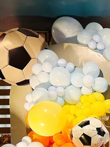 A close-up of a sports-themed party, showing a large football foil balloon as part of the decor.