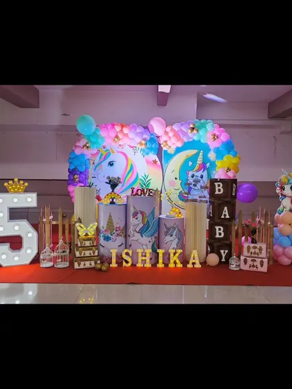 Our unicorn theme is pure magic. This setup for Ishika's birthday features pastel unicorn illustrations on pedestals, a rainbow balloon arch, and light-up letters for an enchanting party.