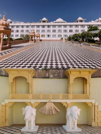 The grandeur of the wedding venue at Radisson Blu Udaipur paired with a creative shot of the bride's lehenga displayed against the palace architecture.