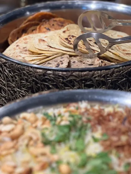 A glimpse of a Diwali buffet spread, featuring a large platter of biryani and a basket of assorted Indian breads.