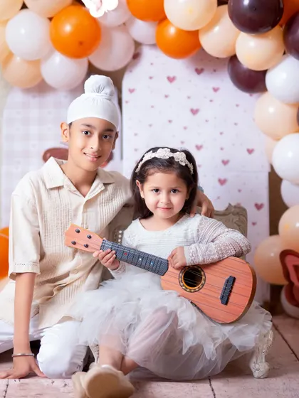 A fun sibling portrait with a toy ukulele. Using props can bring out the playful side of children and create unique and memorable photos.