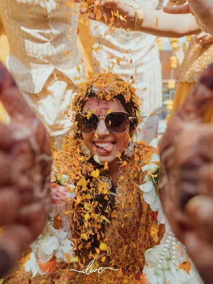 A fun, first-person perspective of the bride during her Haldi, her face covered in turmeric and her expression full of playful energy.