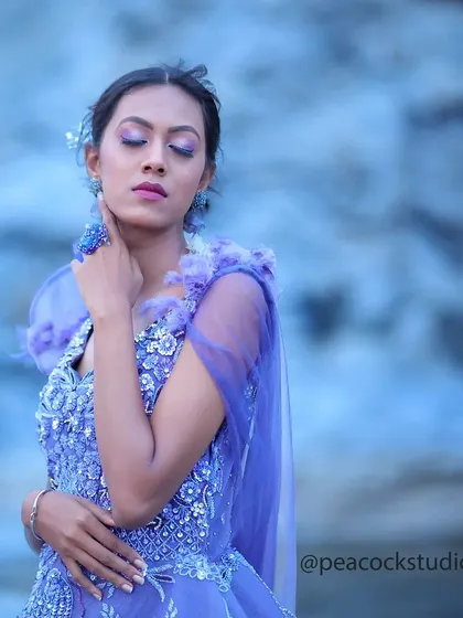 An ethereal portrait of a model in a heavily embellished lavender gown, with a soft, dreamy blue background.