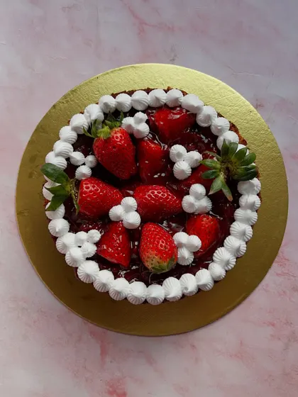 An overhead shot of our fresh strawberry cake, showcasing the generous topping of glossy strawberries and cream.