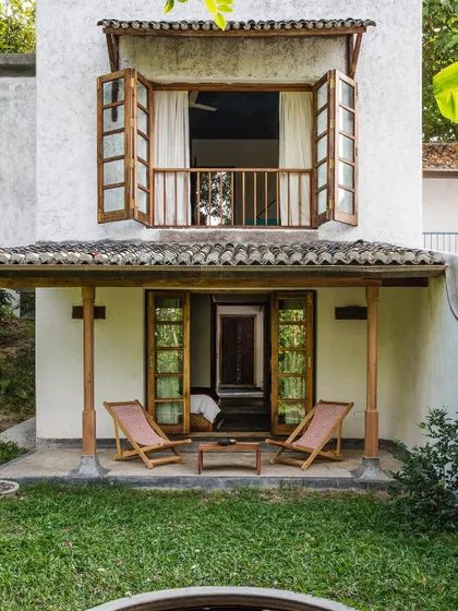 The exterior of the Tower and Garden rooms at Jalakara, showing the classic combination of white walls, wooden balconies, and tiled roofs.