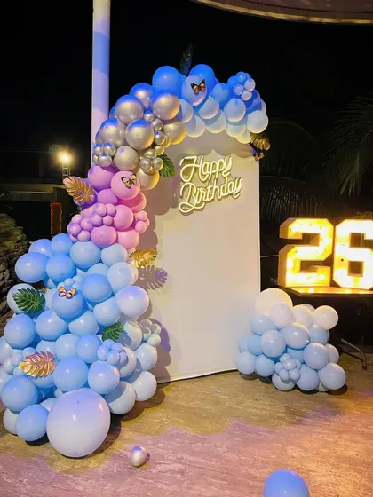 A beautiful blue and pink theme for a 26th birthday. This outdoor setup includes a balloon garland on an arched backdrop, a neon sign, and light-up numbers.