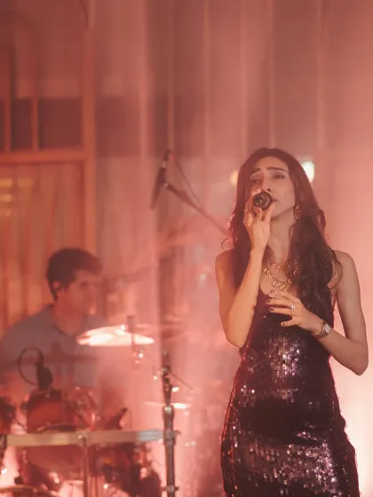 Performing with the band in atmospheric lighting at The Lupa Gram. We work with the venue's ambiance to create a cohesive and immersive show.