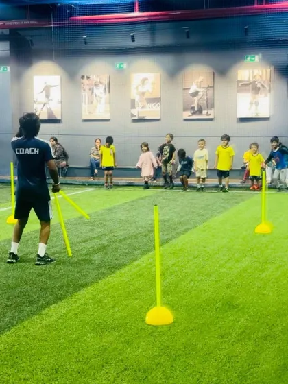 A coach sets up training poles for our youngest group. We use colorful and safe equipment to make learning football skills exciting for toddlers.