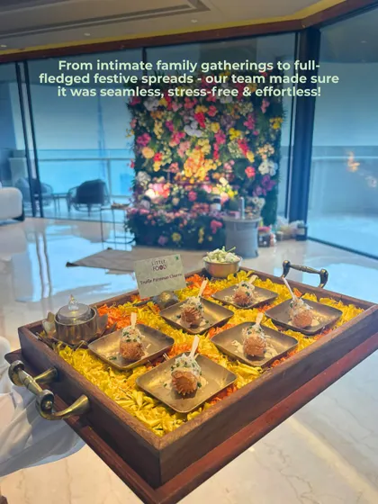 A glimpse of our seamless festive service. A server holds a tray of appetizers in a beautifully decorated home with a stunning floral wall, showing how we cater to everything from intimate family gatherings to large festive spreads.