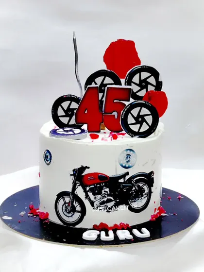 A cake for a Royal Enfield bike rider, featuring edible wheels and a printed image of the classic bike.