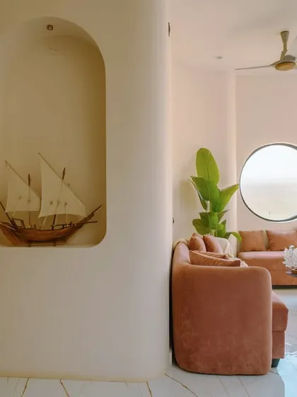 An arched niche displays a decorative ship, a personal touch that adds to the story of the 'Sukoon' home, complemented by a blush-toned sofa.