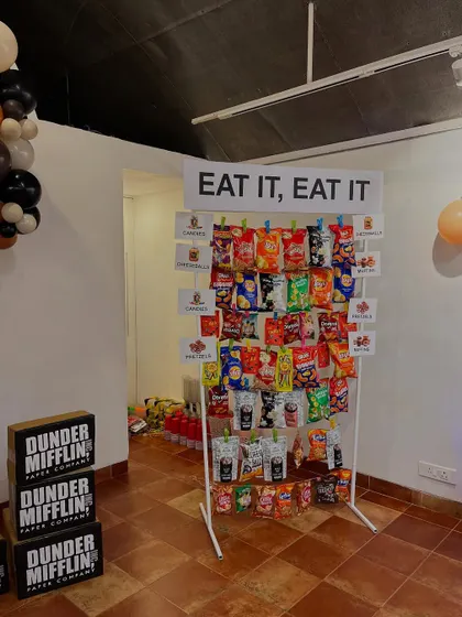 We included iconic inside jokes from the show, such as poorly labeled balloons, a "Rude that you're leaving" farewell banner, and a snack wall with the sign "Eat it, eat it".