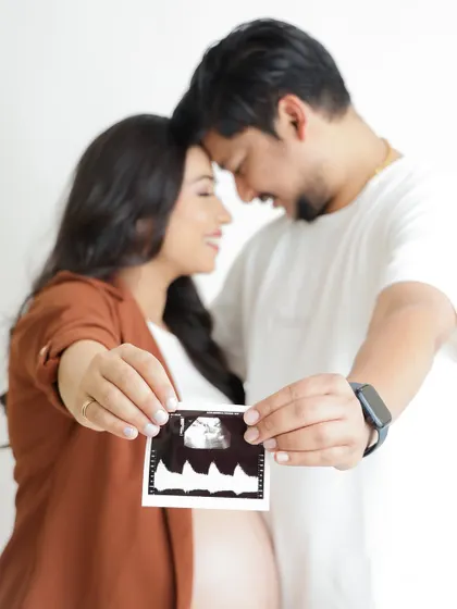 A close-up shot focusing on the sonogram, with the loving couple blurred in the background. A creative way to announce their pregnancy.