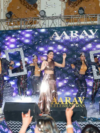 A daughter's stylish performance at Chomu Palace. The use of props like silver frames and a confetti shower adds a modern and fun twist to her Bollywood dance number.