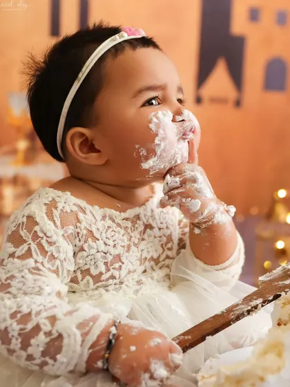A side profile capturing a candid moment of the baby enjoying her first taste of birthday cake.