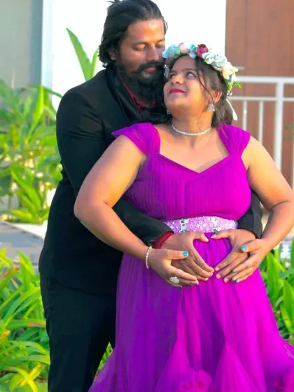 A close-up couple's portrait where both partners make a heart shape on the baby bump. This pose is a sweet and symbolic way to show love for your coming baby.