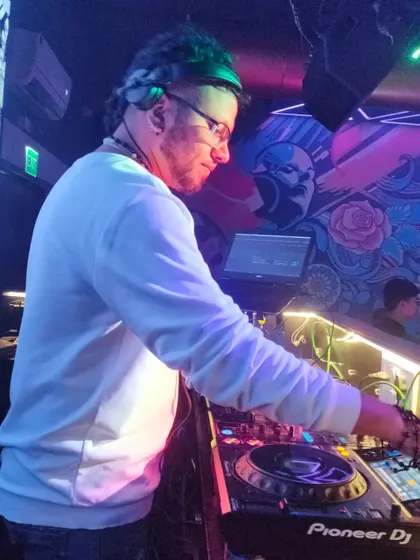 A side view of me performing in a club with cool, artistic wall murals. The lighting adds to the underground vibe of the night.