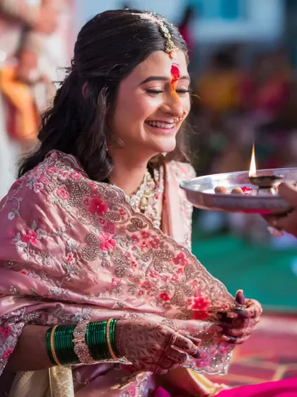A beautiful candid moment of the bride participating in a ritual, her smile genuine and heartwarming.