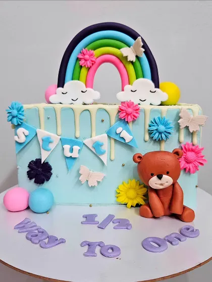 Stuti's half birthday cake. This chocolate truffle cake celebrates her being 6 months old with a cute teddy bear, a rainbow, and colorful flowers.