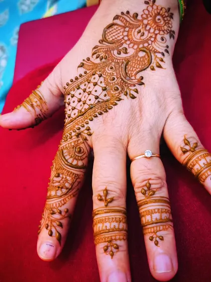 A graceful party design on the back of the hand, combining a peacock motif with a jaali (net) pattern.