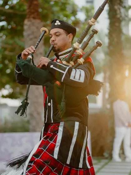 A bagpiper in traditional Scottish attire adds a touch of international flair and regal sound to the Bridgerton-themed celebration.