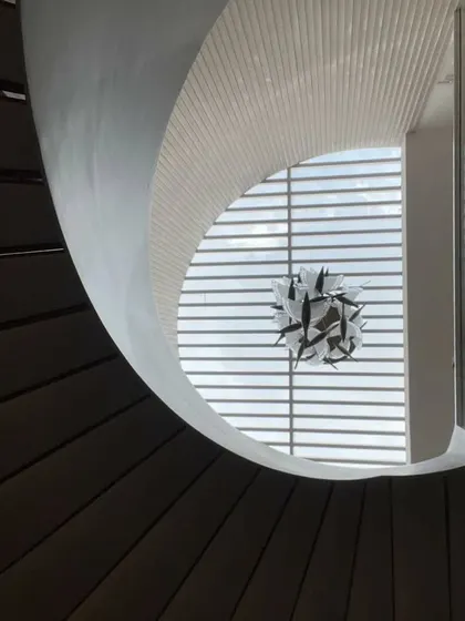 This perspective emphasizes the sculptural quality of the staircase and the custom chandelier, which hangs like a piece of art within the void.