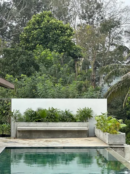 A built-in concrete bench and planter at the edge of the infinity pool. This detail provides extra seating and integrates the pool area with the surrounding greenery.