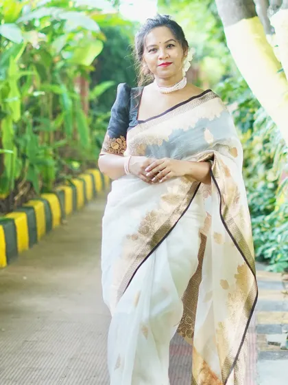 A Banarasi handloom Kora Organza silk saree in white and gold, paired with a contrasting black puff-sleeve blouse.