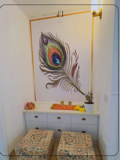 A simple yet elegant pooja space created in a niche. The wall is decorated with a beautiful hand-painted peacock feather, and the low ottomans provide comfortable seating.