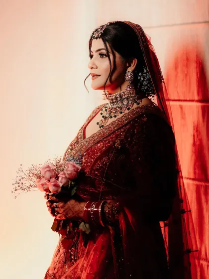 A beautiful bridal portrait with dramatic red and white lighting, holding a bouquet of pink roses.