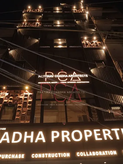A wide night view of the Chadha Properties office, showing its context within the street and how the lighting makes it a local landmark.