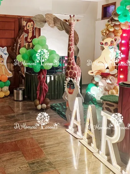 Detailed props for the jungle theme, including a tall giraffe, Rafiki cutout, and custom light-up letters, adding to the safari adventure feel.