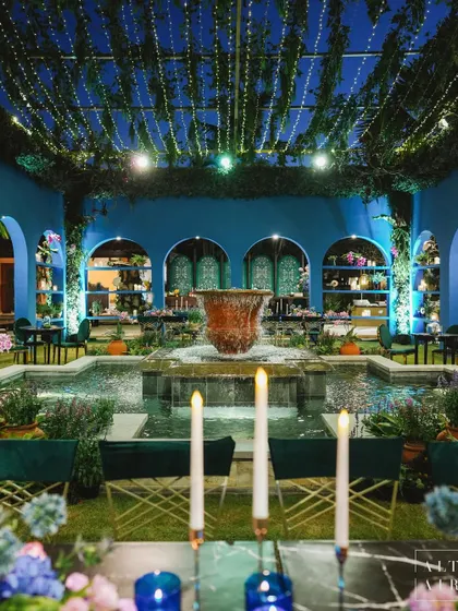 The pre-cocktail area for 'Midnight Mirage', transformed into an enchanting alfresco patio. The space featured a central fountain, graceful arches, and a ceiling of lush greenery and fairy lights.