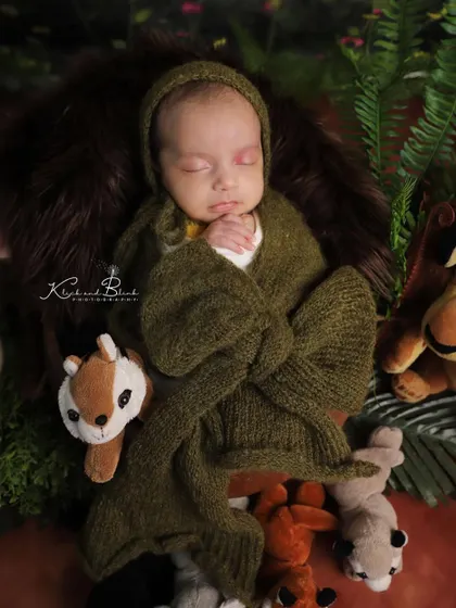 Another pose from the wildlife session. Here, the baby is swaddled in a cozy green wrap, still surrounded by his favorite jungle animals.