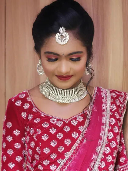 A beautiful look for a half saree function. The makeup is bold and celebratory, with a red smokey eye and a matching red lip that complements her velvet lehenga.