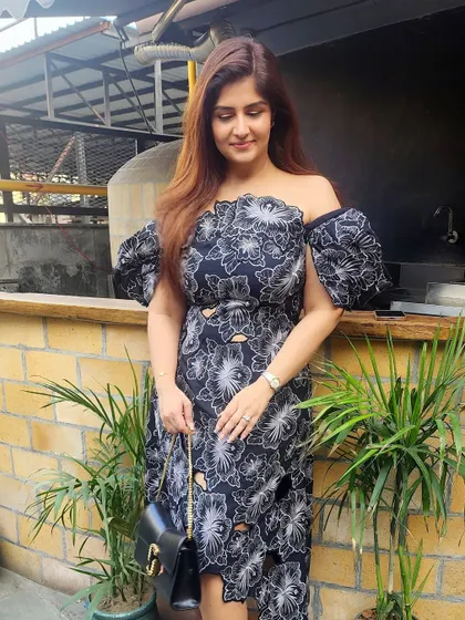 A beautiful off-shoulder black dress with white floral embroidery and an asymmetrical hemline, perfect for a cocktail party or evening event.