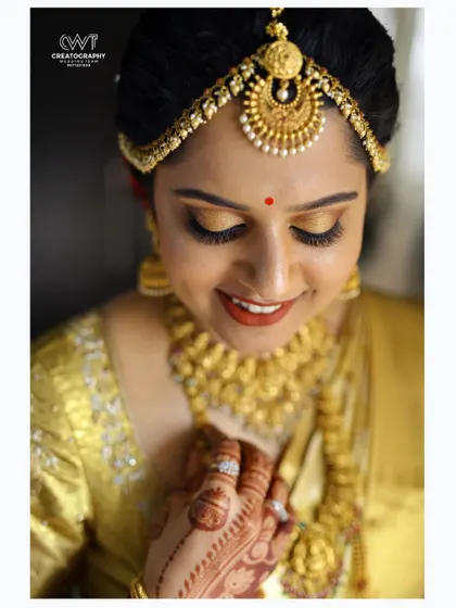A serene, close up bridal portrait with eyes closed, highlighting the intricate details of her gold jewelry and henna.