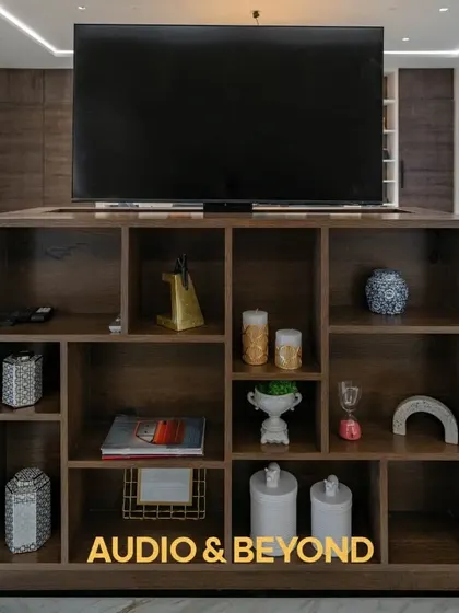 A close-up of the custom TV lift cabinet. The television is shown fully elevated from the bookshelf, providing an excellent viewing angle while serving as a functional and stylish piece of furniture.