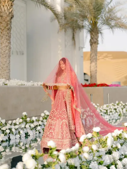 The bride's final walk down an aisle of flowers. The reflection on the mirrored path and the ocean backdrop create a stunning, dreamlike scene.