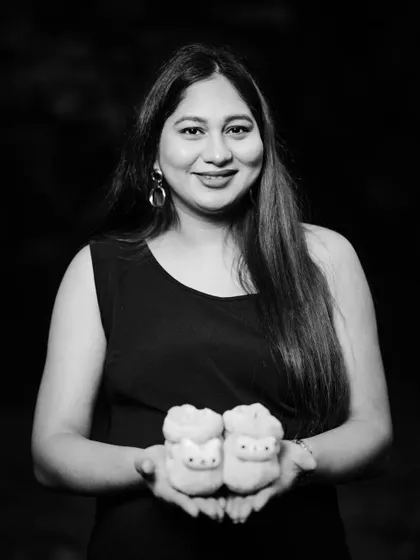 A classic black and white portrait of a mother-to-be holding a pair of baby booties. The focus is on her happy expression and the anticipation of her new arrival.