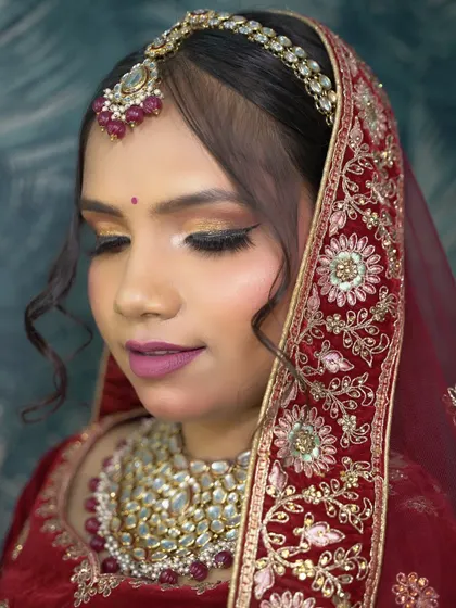 A glamorous bridal look taught in a recent makeup batch. The focus is on a shimmery, golden eye and a soft matte lip, paired with a beautiful red lehenga.