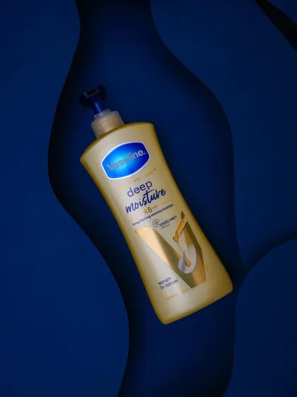 An overhead shot of the Vaseline lotion, using the wavy blue paper backdrop to create interesting shadows and a sense of depth, highlighting the product from a different perspective.