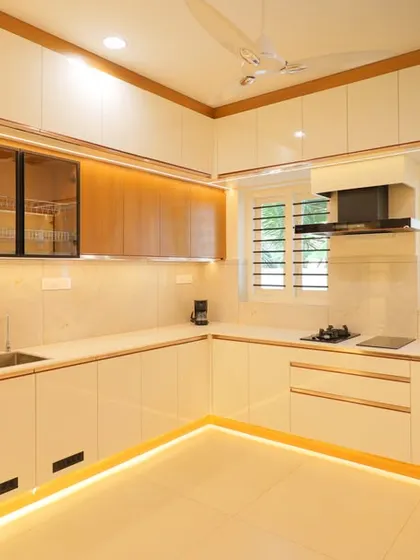This U-shaped kitchen maximizes counter space and storage. The glossy white cabinets and wood accents create a timeless look, while the lighting ensures a well-lit workspace.