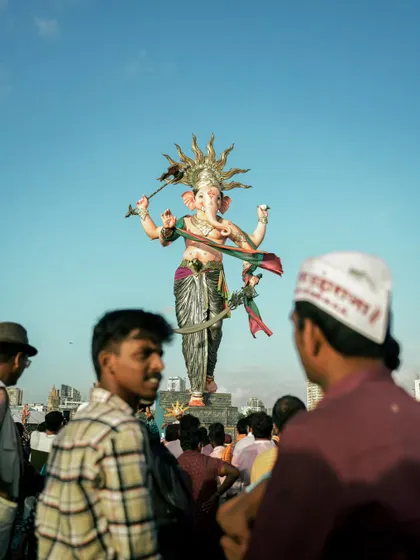 A street level view of the Mumbaicha Raja idol, seen from the perspective of the devotees in the crowd. It captures the feeling of being part of the massive procession.